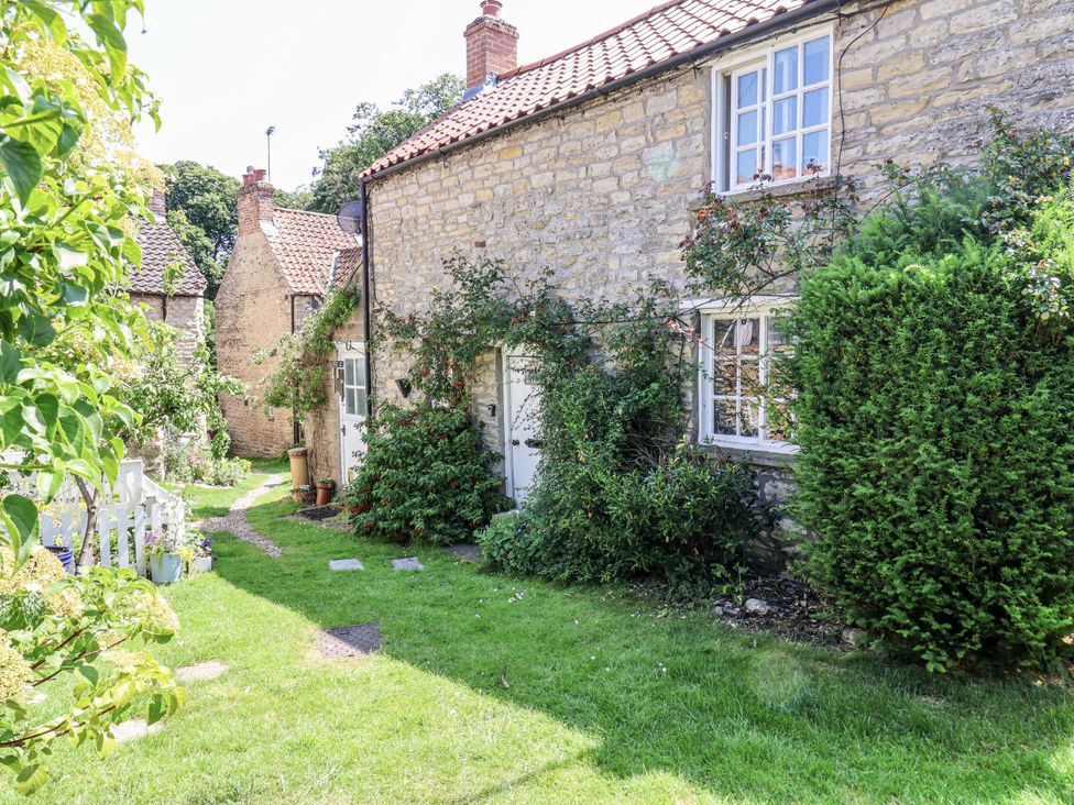A garden with stone houses and a pathway at Hemdin Cottage in Thornton Dale