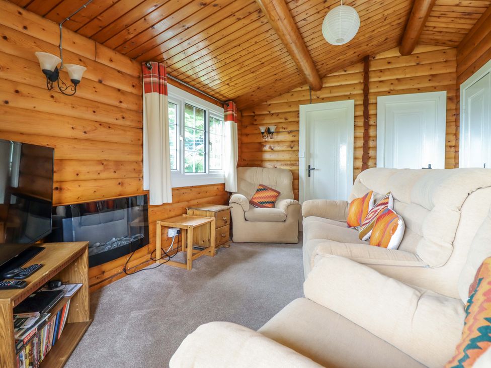 A living room with sofa and television at Y Bwthyn Pren, Cabin 209, Trawsfynydd