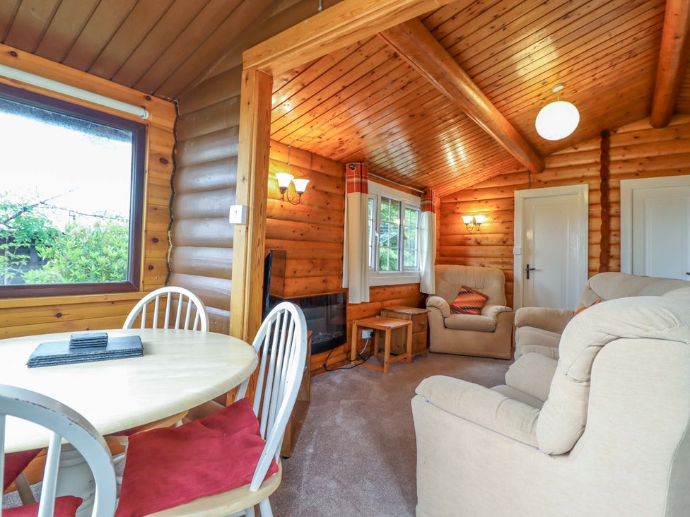 A living room with a dining table and sofa at Y Bwthyn Pren, Cabin 209, Trawsfynydd