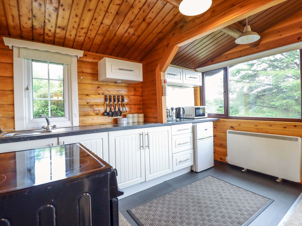 A kitchen with a sink, stove, and refrigerator at Y Bwthyn Pren, Cabin 209, Trawsfynydd