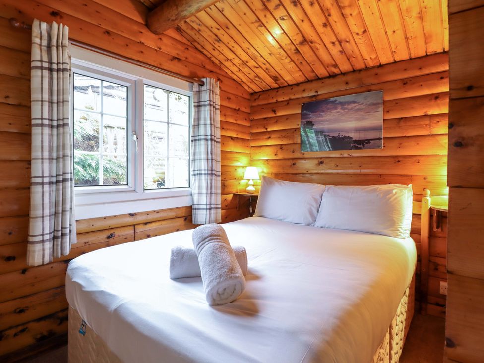 A bedroom with a bed and window at Y Bwthyn Pren, Cabin 209, Trawsfynydd