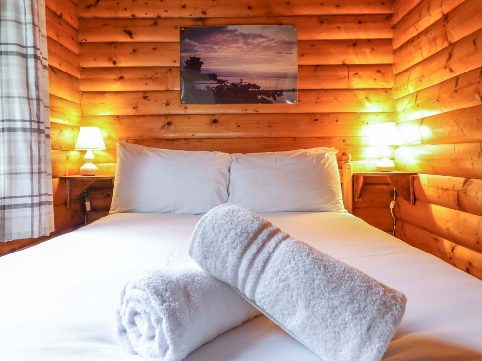 A bedroom with a bed and towels at Y Bwthyn Pren, Cabin 209, Trawsfynydd
