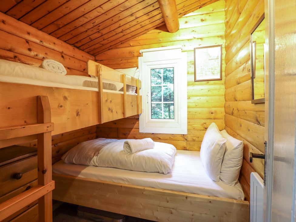 A bedroom with a bunk bed and a single bed at Y Bwthyn Pren, Cabin 209, Trawsfynydd