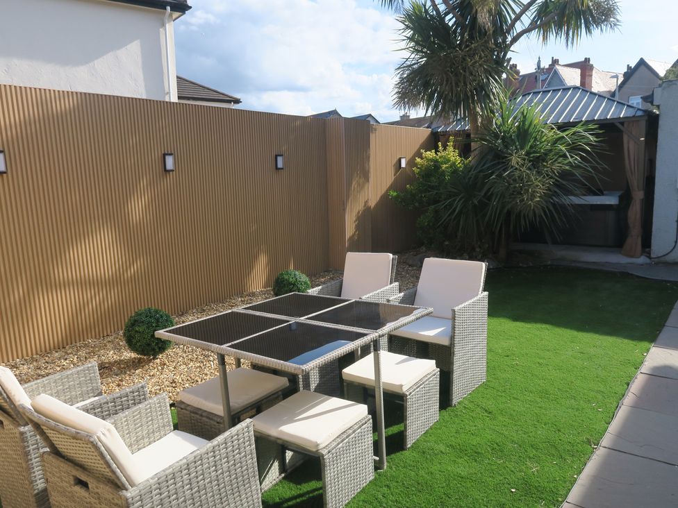 A garden with a dining table and chairs at Seabreeze in Llandudno