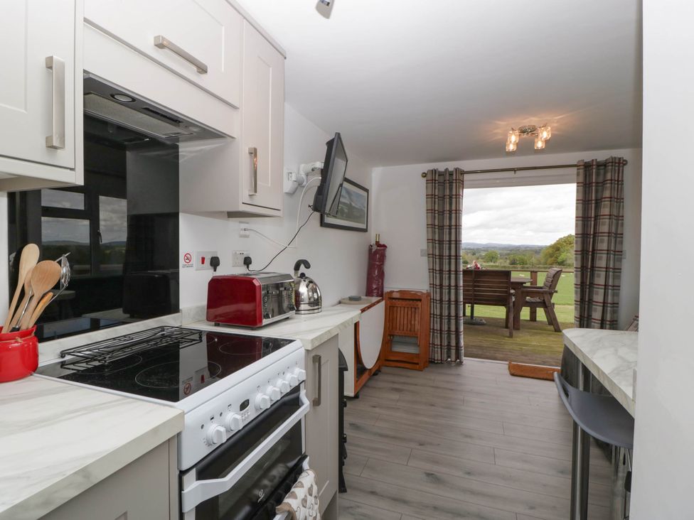 A kitchen area with stove toaster kettle and utensils with a view of outdoor seating at Twilight in Raglan