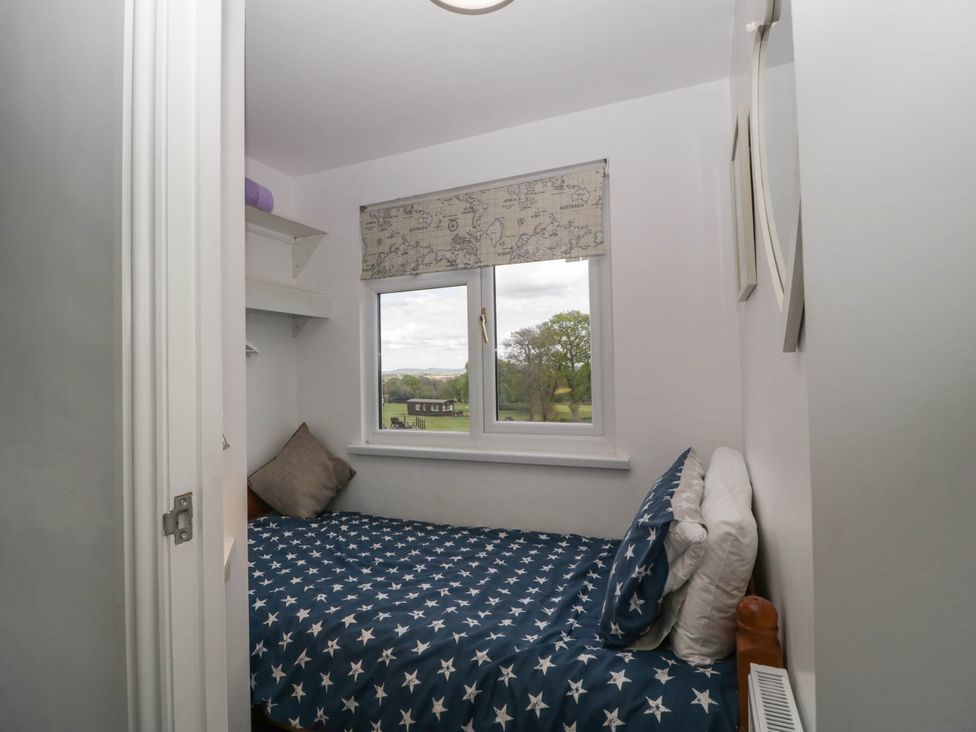 A small bedroom with a single bed covered in star patterned bedding and a window with a map printed blind at Twilight in Raglan