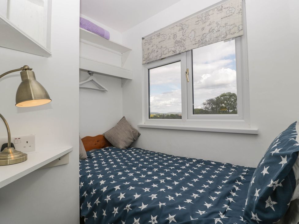A small bedroom with a bed covered in star patterned bedding a window with a world map blind and a desk lamp at Twilight in Raglan