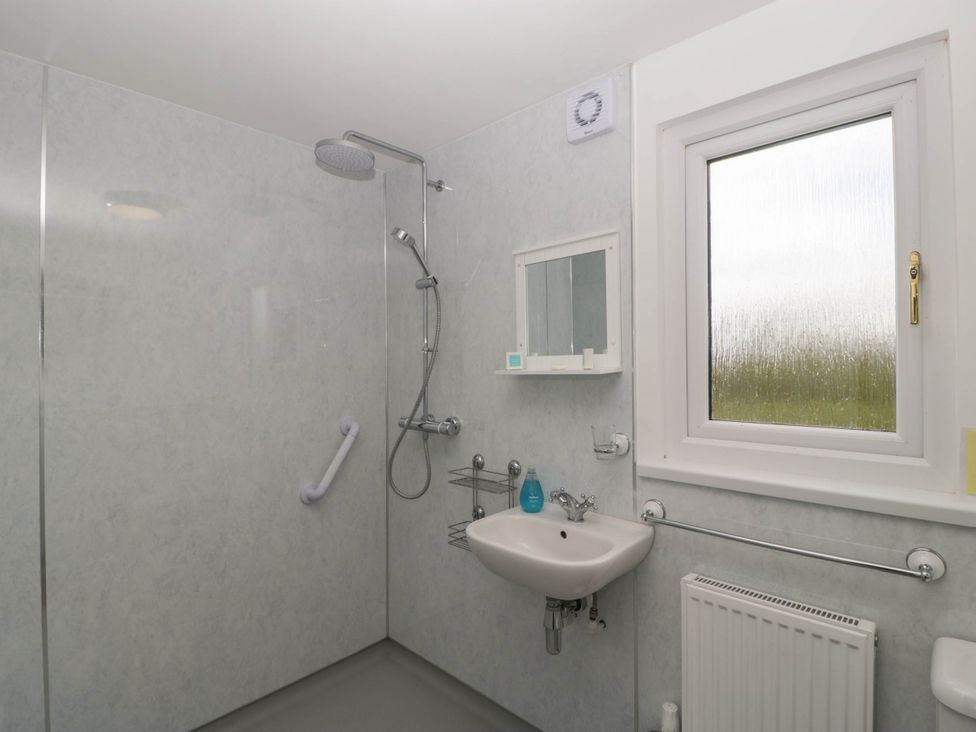 A bathroom with a walk in shower sink mirror and window at Twilight in Raglan