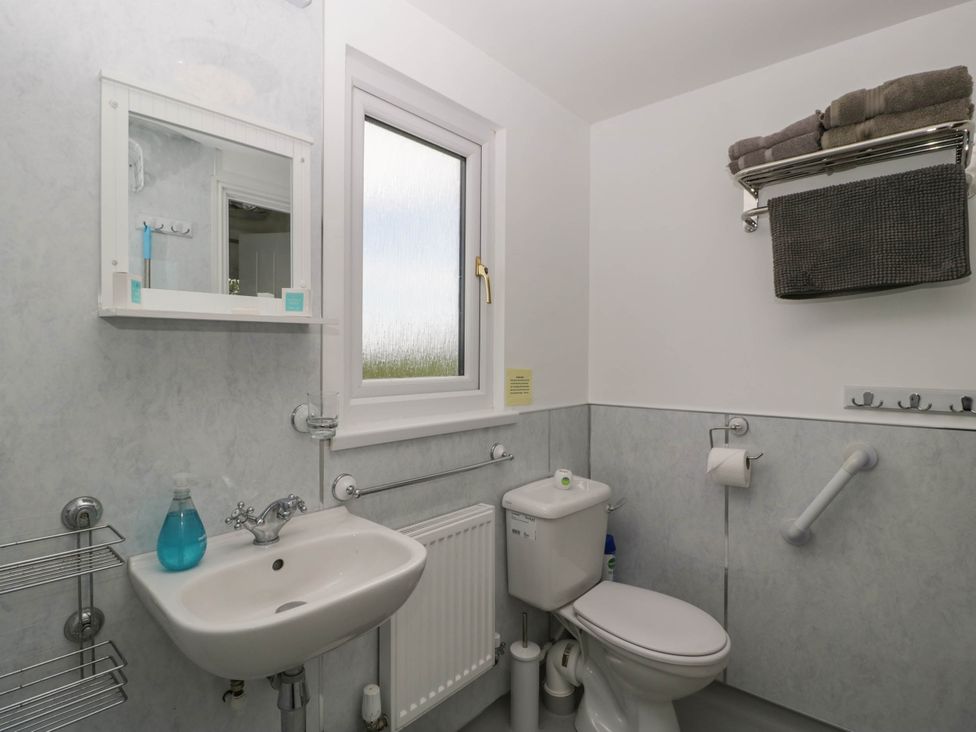 A bathroom with a sink toilet mirror shelf towels and a window at Twilight in Raglan