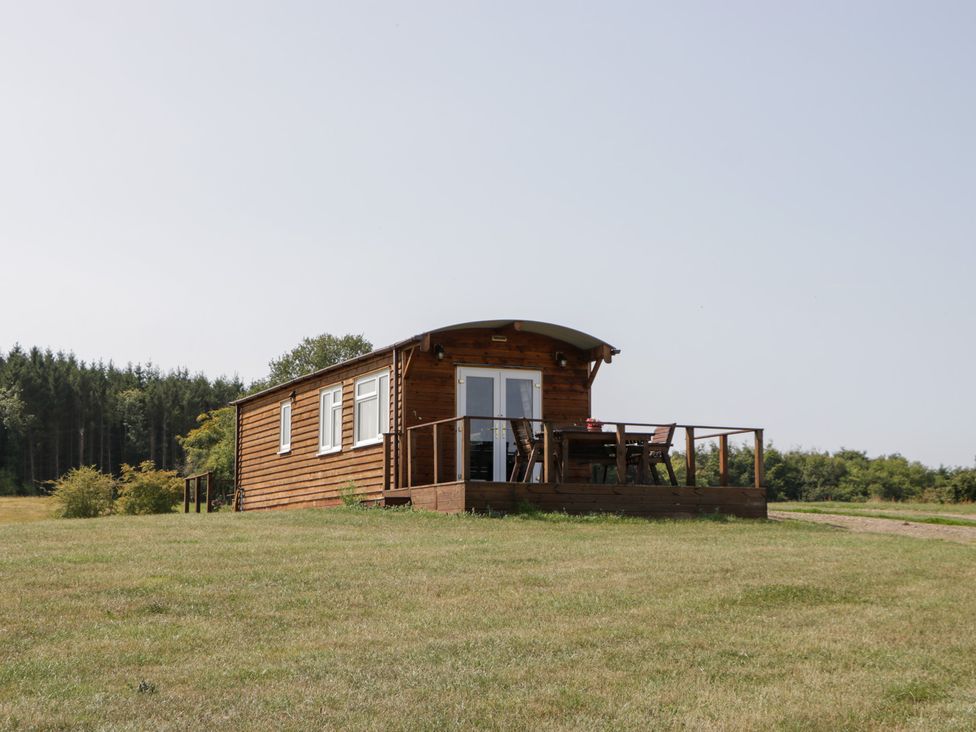 A cabin with a deck and chairs at Twilight in Raglan