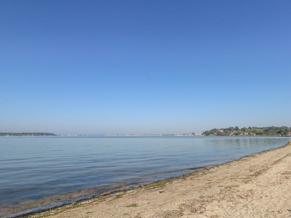 A sandy beach with calm water and clear sky at 6 Red Sails in Sandbanks
