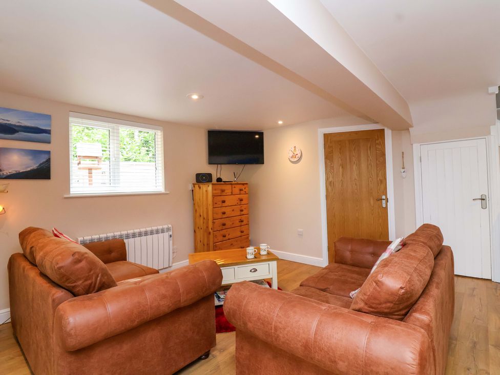 A living room with a television and chest of drawers at Poddington Cottage