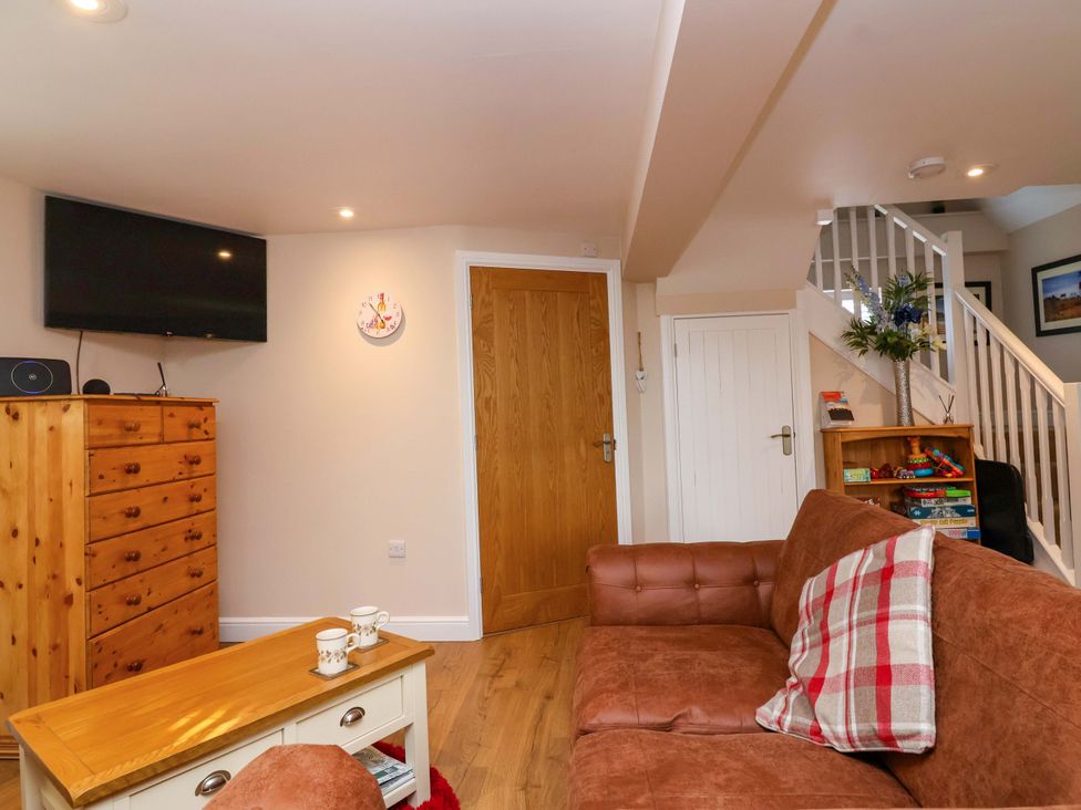 A snug with a sofa and television at Poddington Cottage