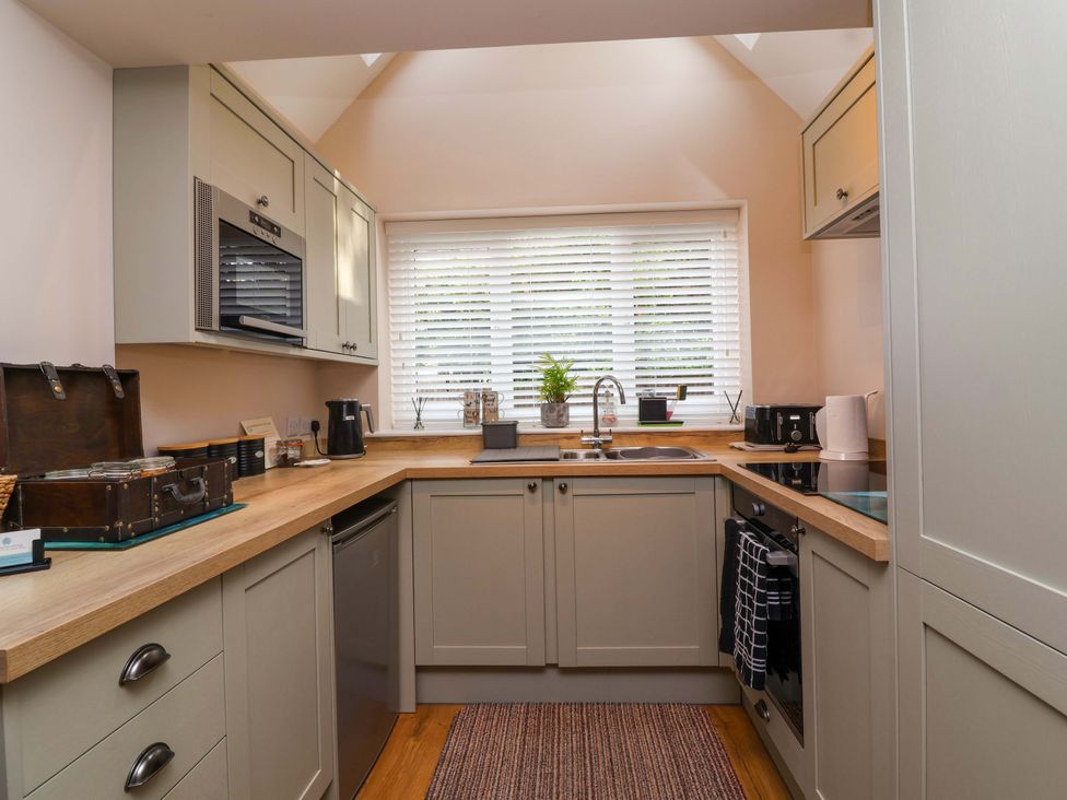 A kitchen with cabinets and appliances at Poddington Cottage