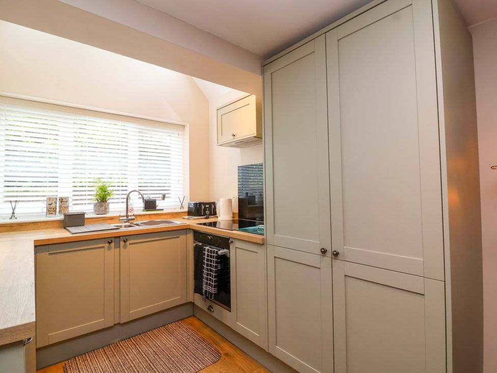 A kitchen with cabinets and a sink at Poddington Cottage