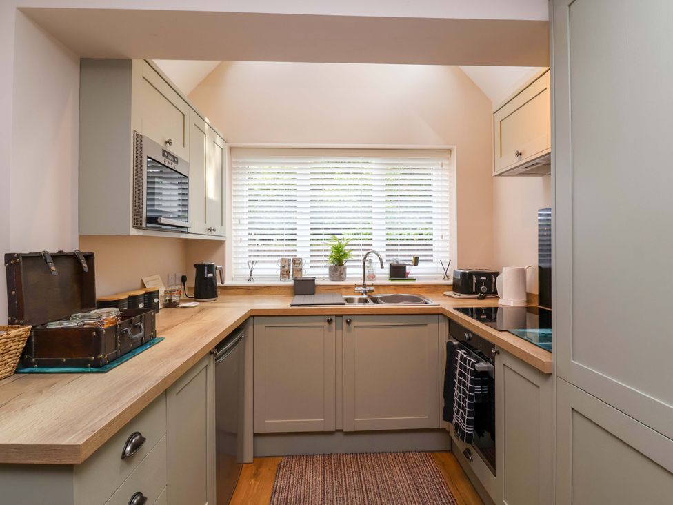 A kitchen with a sink, stove, and small appliances at Poddington Cottage