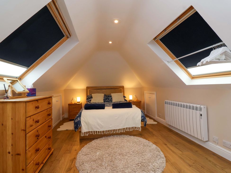 A bedroom with a bed and wooden furniture at Poddington Cottage