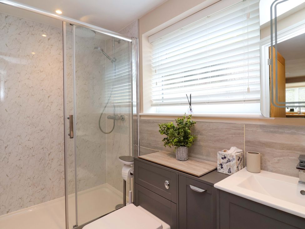A bathroom with a shower, toilet, and sink at Poddington Cottage