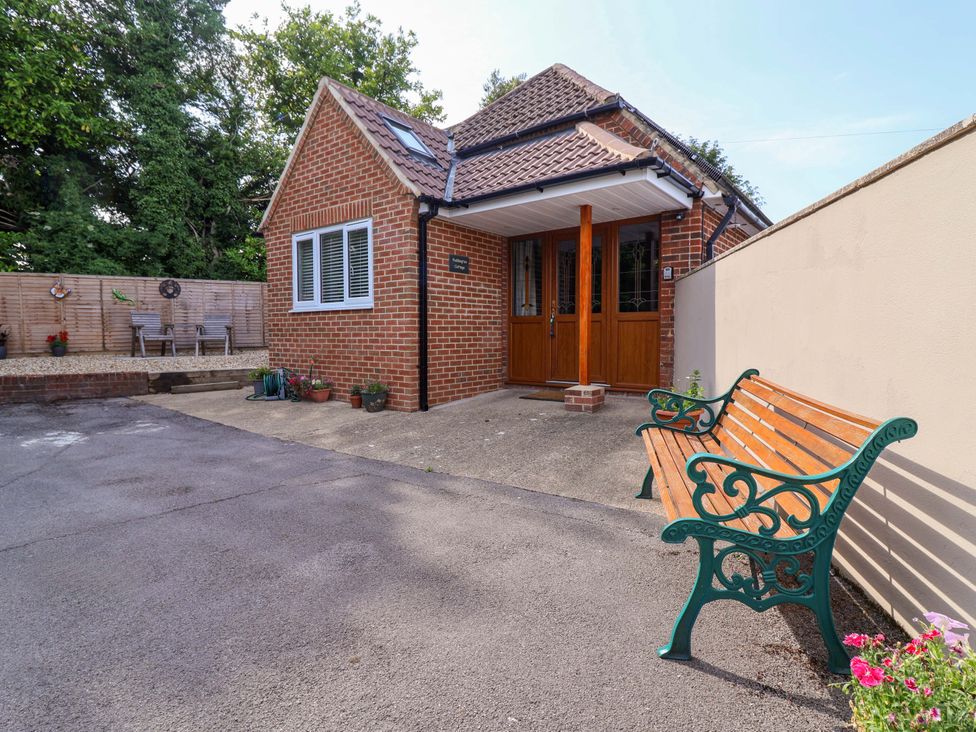 An outdoor area with a house entrance and benches at Poddington Cottage