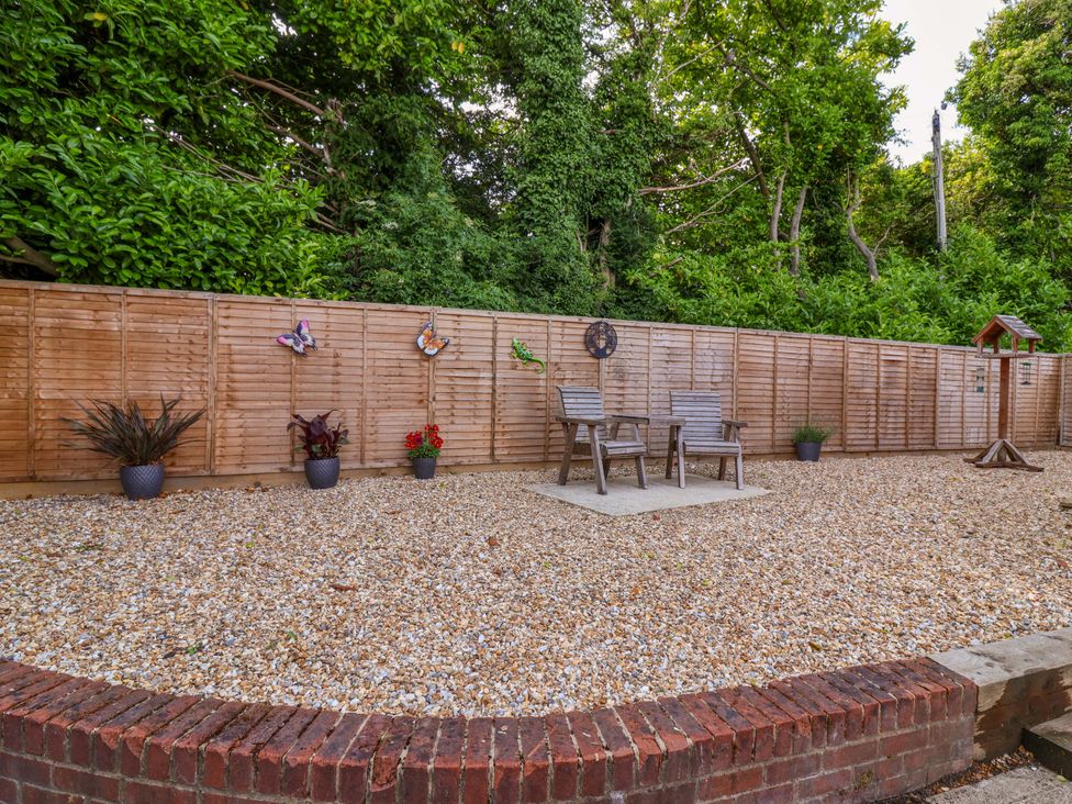 A garden with gravel surface and wooden fence at Poddington Cottage