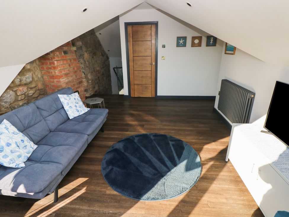 A living room with a sofa and television at 10 Brython Place Tenby