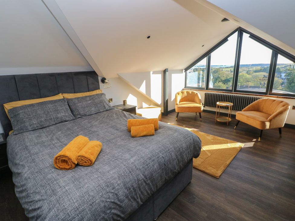 A bedroom with a bed and chairs at 10 Brython Place in Tenby