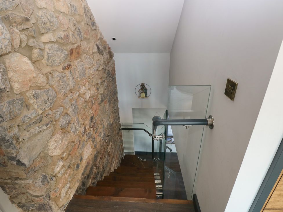 A staircase with a stone wall and glass handrail at 10 Brython Place Tenby