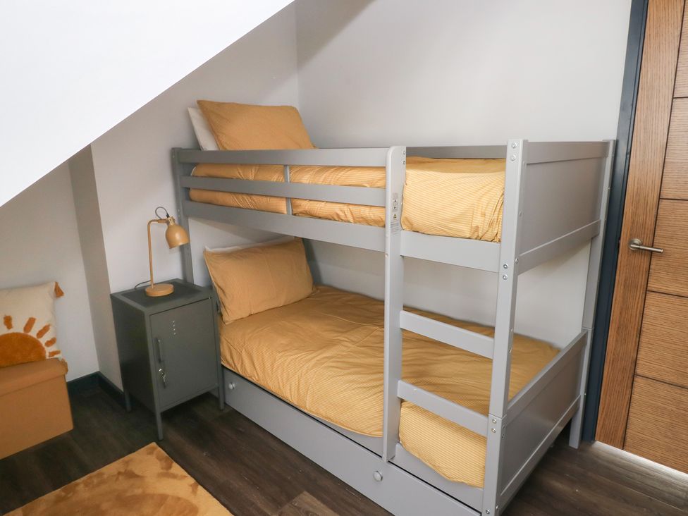 A bunk bed with yellow bedding and a nightstand in the bedroom at 10 Brython Place Tackley