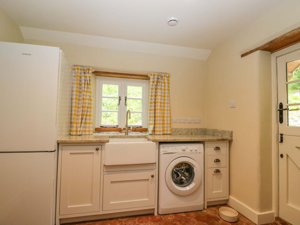 A kitchen with a sink and washing machine at Keepers Cottage in Devizes