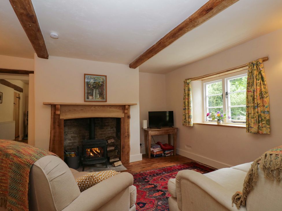 A living room with a fireplace and television at Keepers Cottage in Devizes