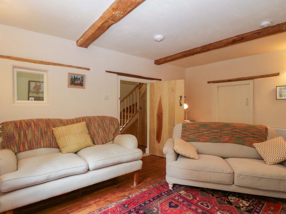 A living room with sofas and a rug at Keepers Cottage in Devizes