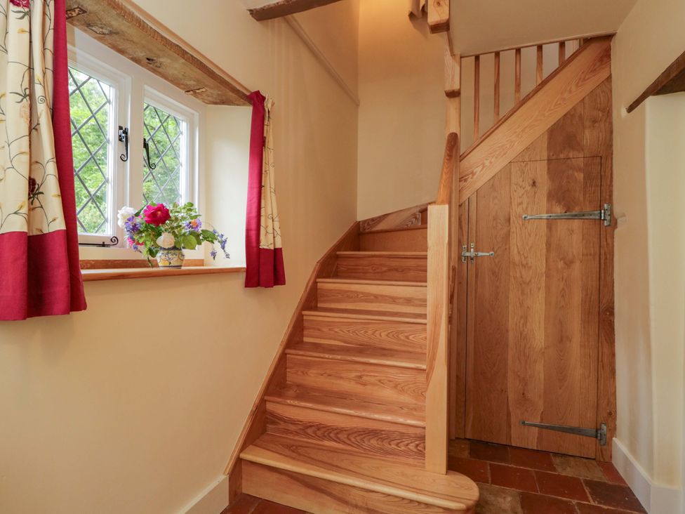 A hallway with a staircase and window at Keepers Cottage in Devizes