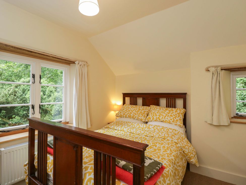 A bedroom with a bed and windows at Keepers Cottage in Devizes