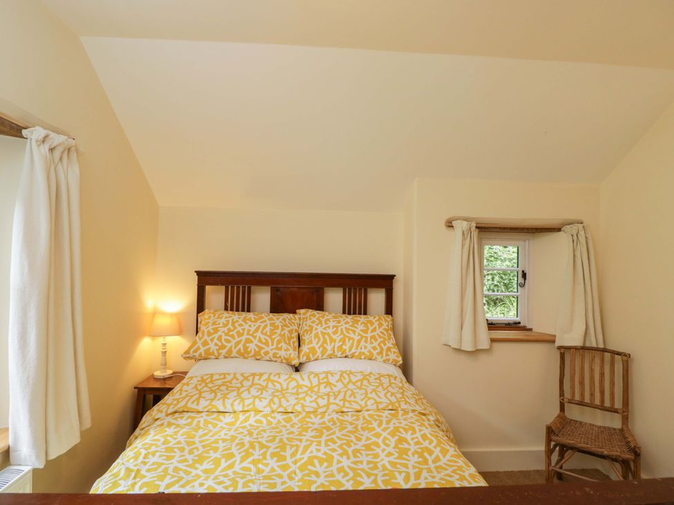 A bedroom with a bed and lamp at Keepers Cottage in Devizes