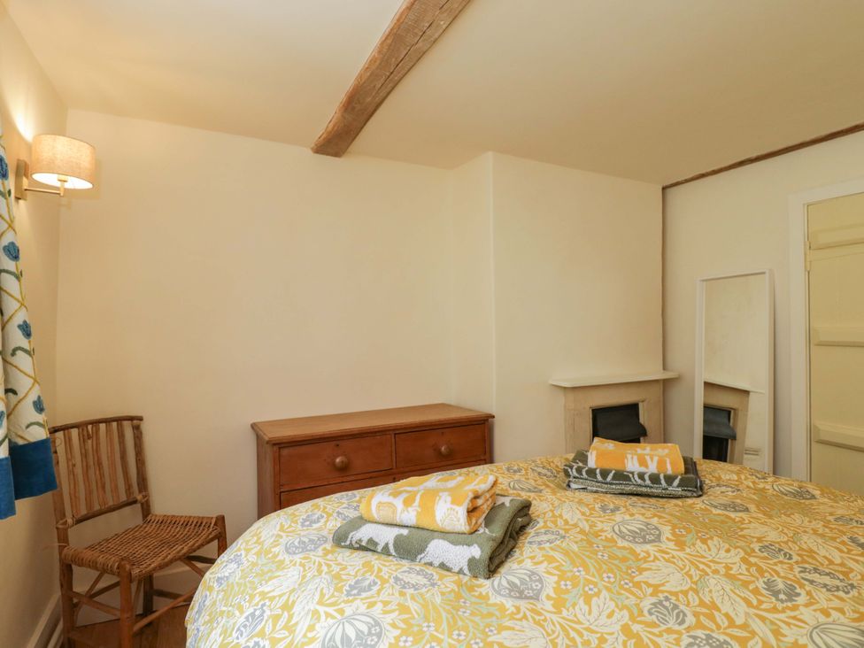 A bedroom with a bed and chair at Keepers Cottage in Devizes
