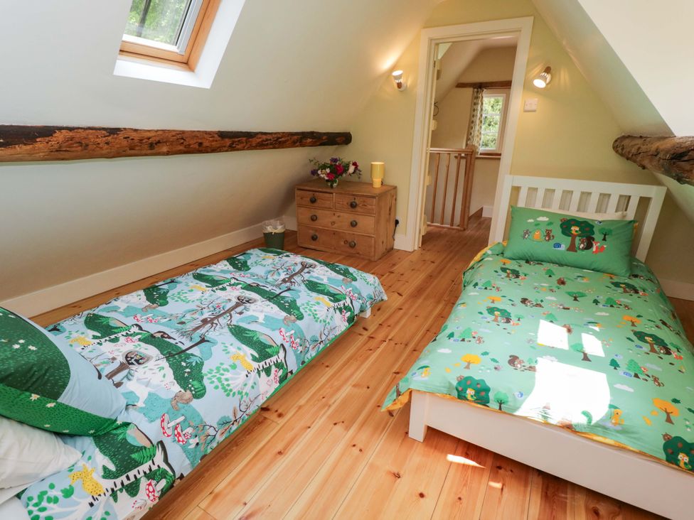 A bedroom with two beds and a bedside table at Keepers Cottage in Devizes