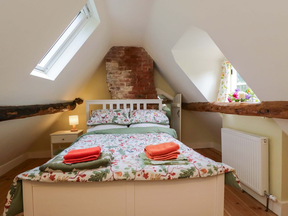 A bedroom with a bed and a nightstand at Keepers Cottage in Devizes