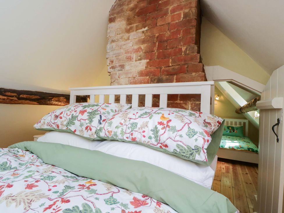 A bedroom with a bed and a brick wall at Keepers Cottage in Devizes