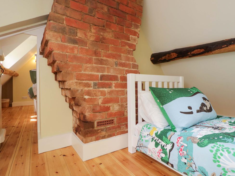 A bedroom with a bed and brick wall at Keepers Cottage in Devizes