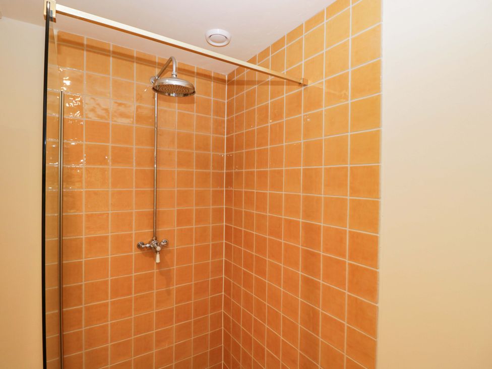 A shower with orange tiles at Keepers Cottage in Devizes