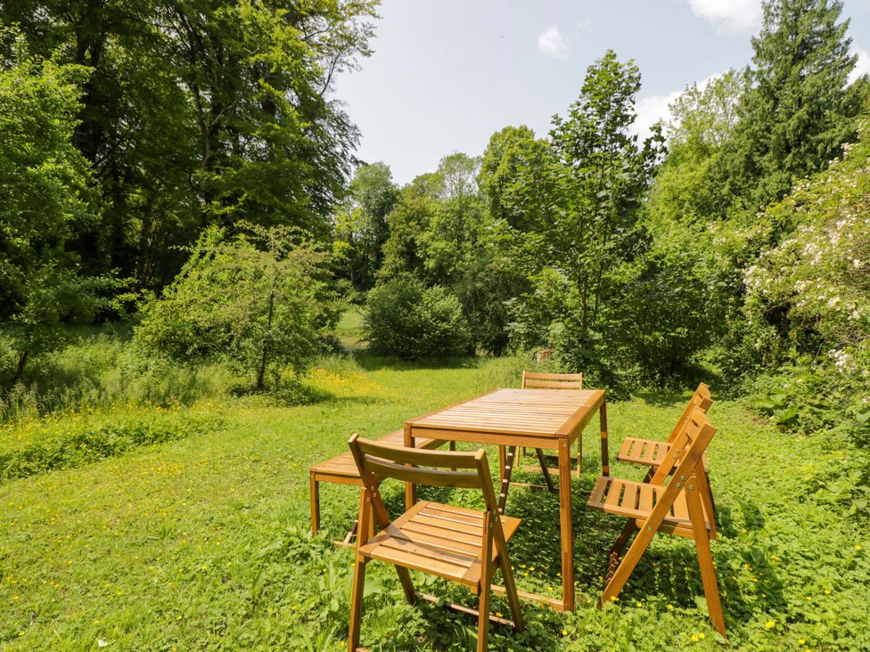 A garden with a wooden table and chairs at Keepers Cottage in Devizes