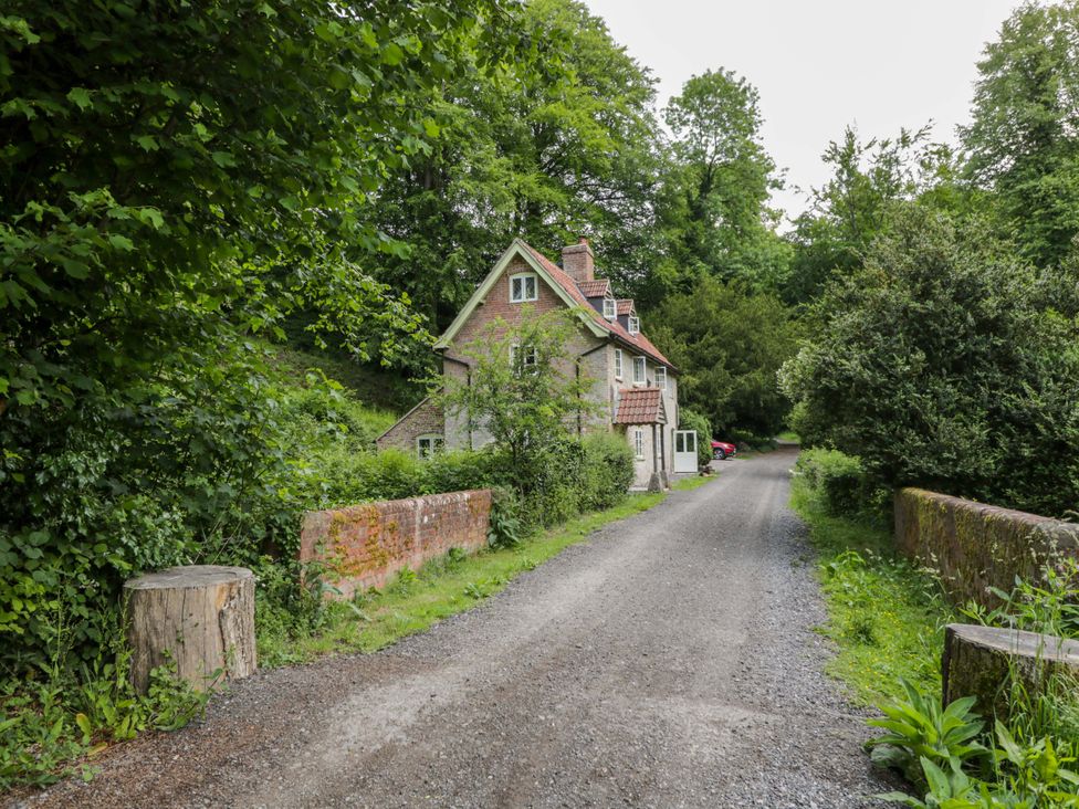 A house on a gravel road surrounded by trees at Keepers Cottage in Devizes