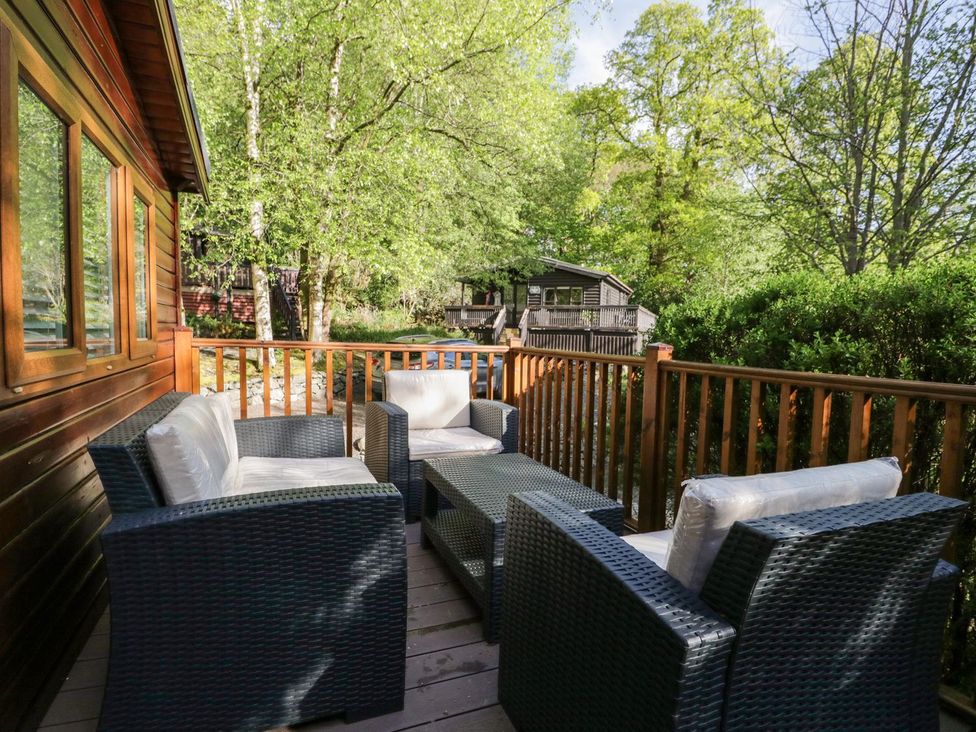 An outdoor balcony with wicker furniture including a table and chairs surrounded by trees at Mere Brook Lodge in White Cross Bay
