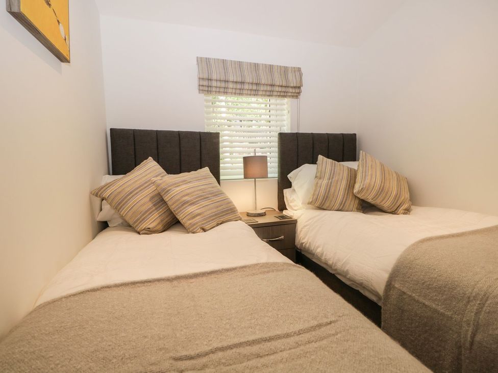 A bedroom with two single beds separated by a bedside table with a lamp at Mere Brook Lodge in White Cross Bay