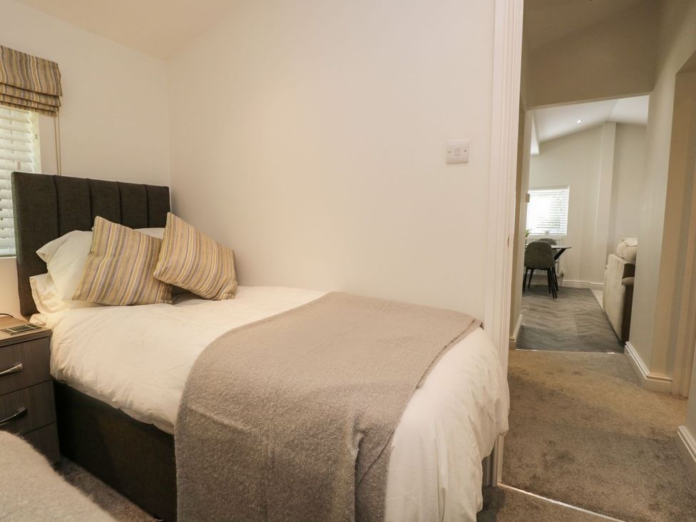 A small bedroom with a single bed pillows and a blanket next to a window with blinds and a nightstand beside it at Mere Brook Lodge in White Cross Bay