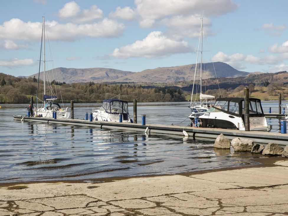 A dock with several boats moored on a lake with hills in the background at Mere Brook Lodge in White Cross Bay