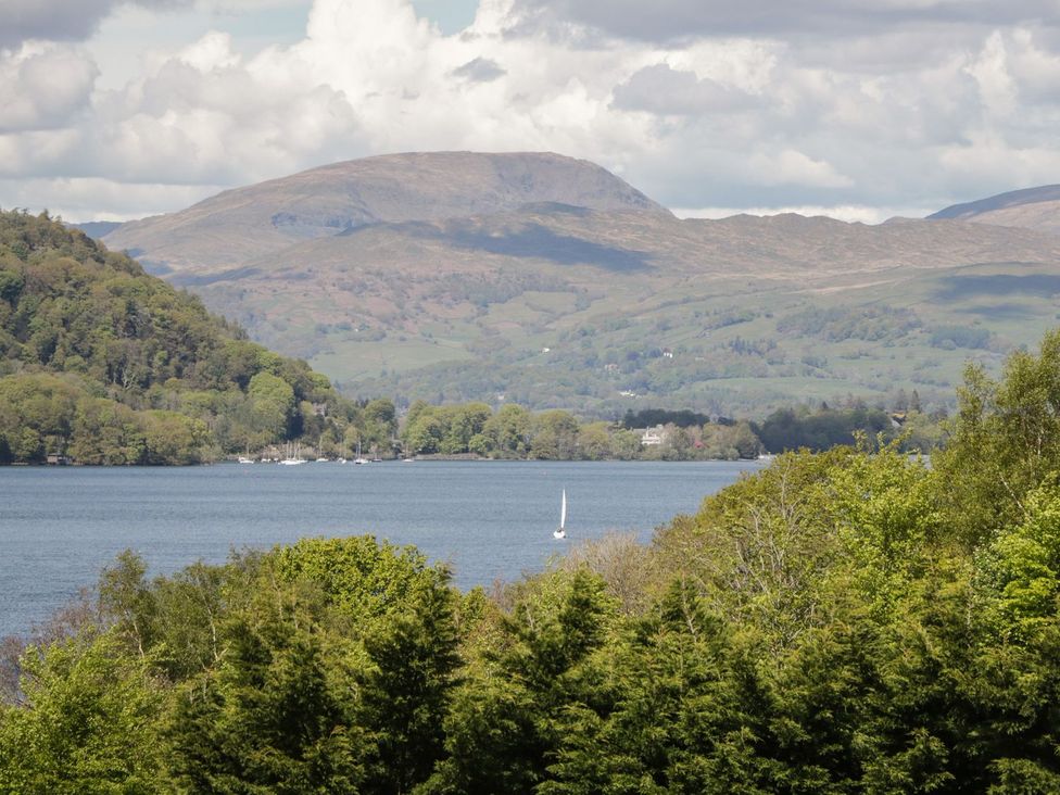 A lake with a sailboat surrounded by trees and hills at Mere Brook Lodge White Cross Bay