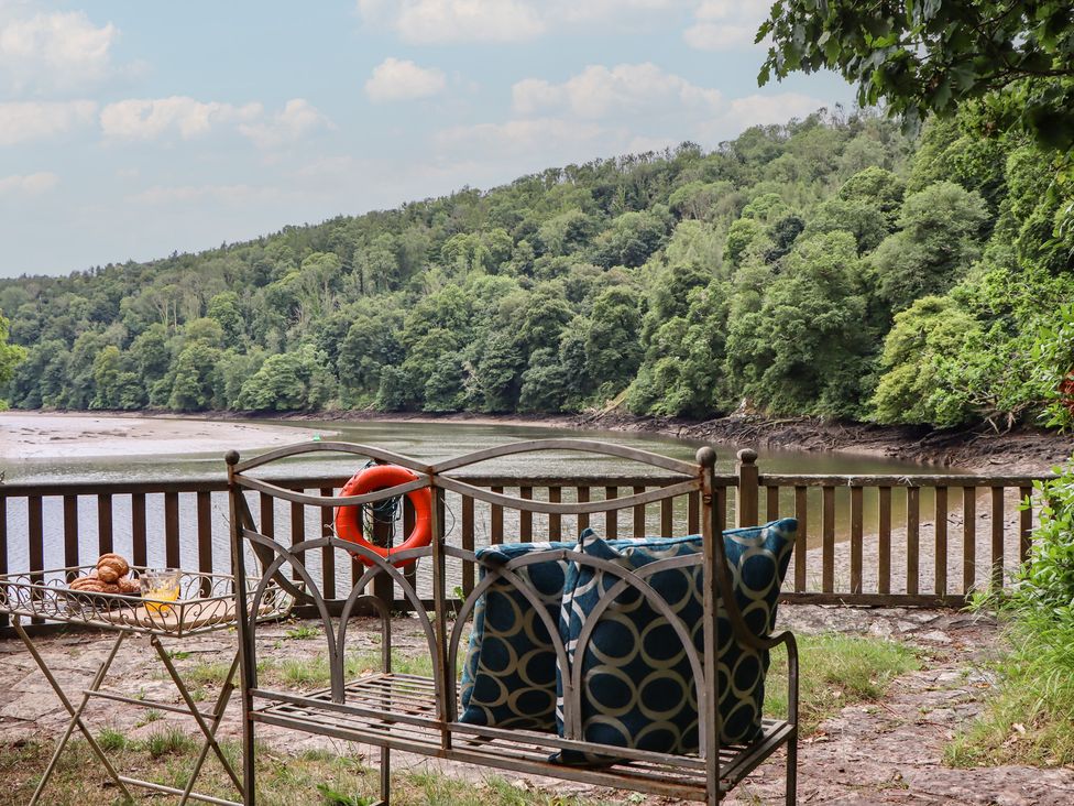An outdoor seating area with a bench and view of the river at The Boat House in Ashprington