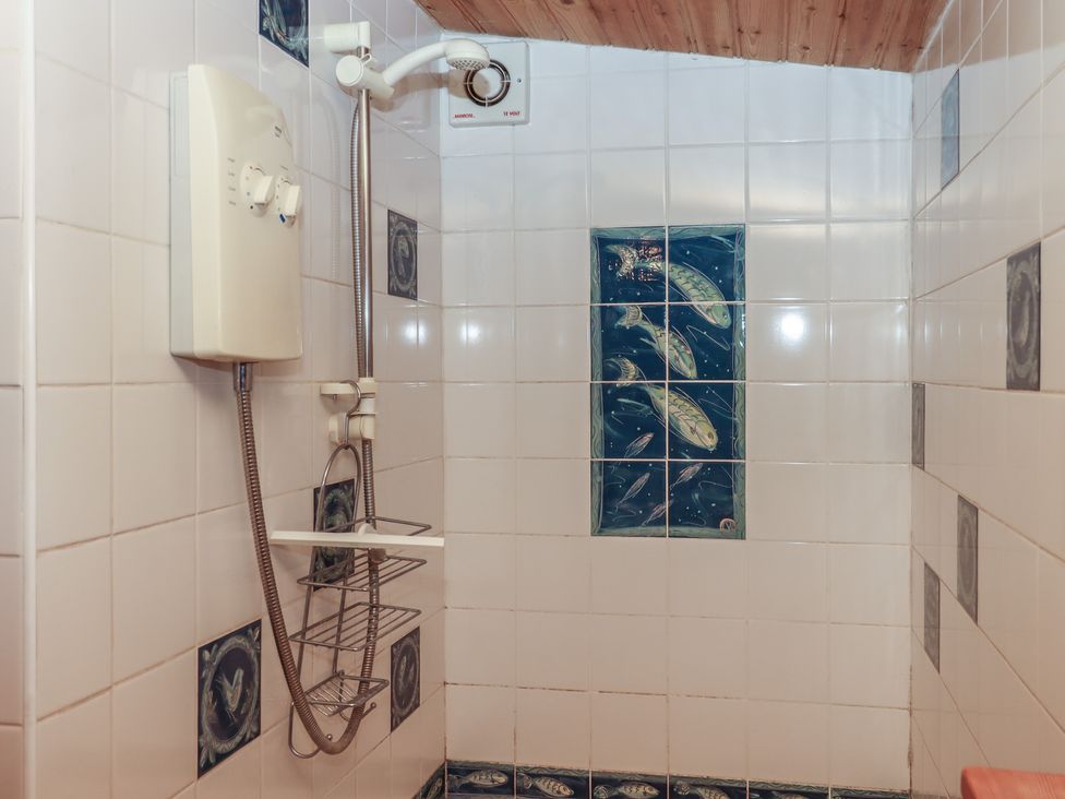 A shower area with wall tiles and an electric shower unit at The Boat House in Ashprington