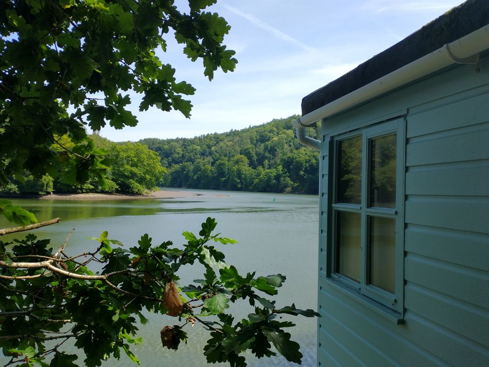 A view of water and trees from the side of a building at The Sharpham Boat House in Ashprington